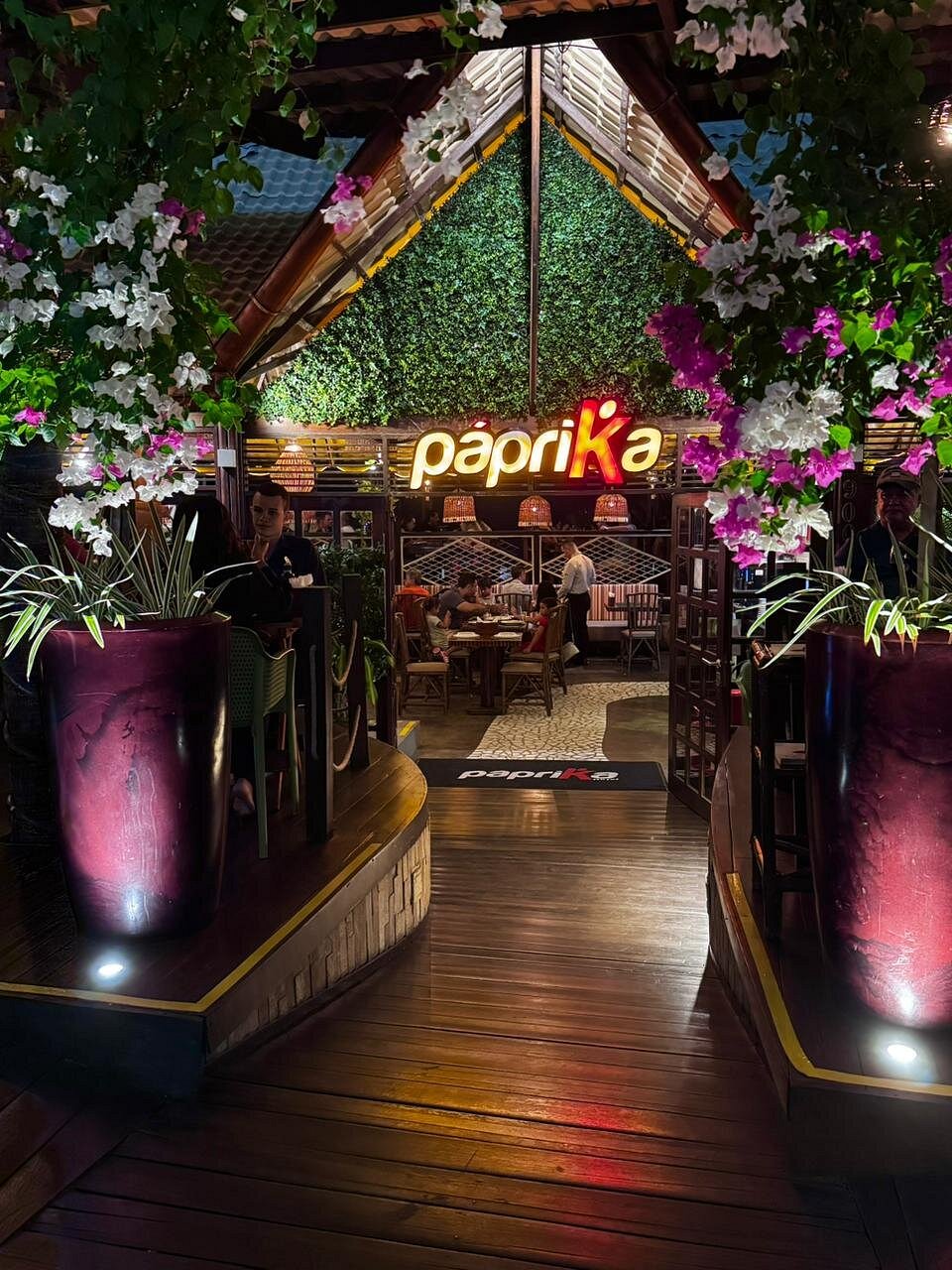Fachada do Páprika à noite, entre buganvílias